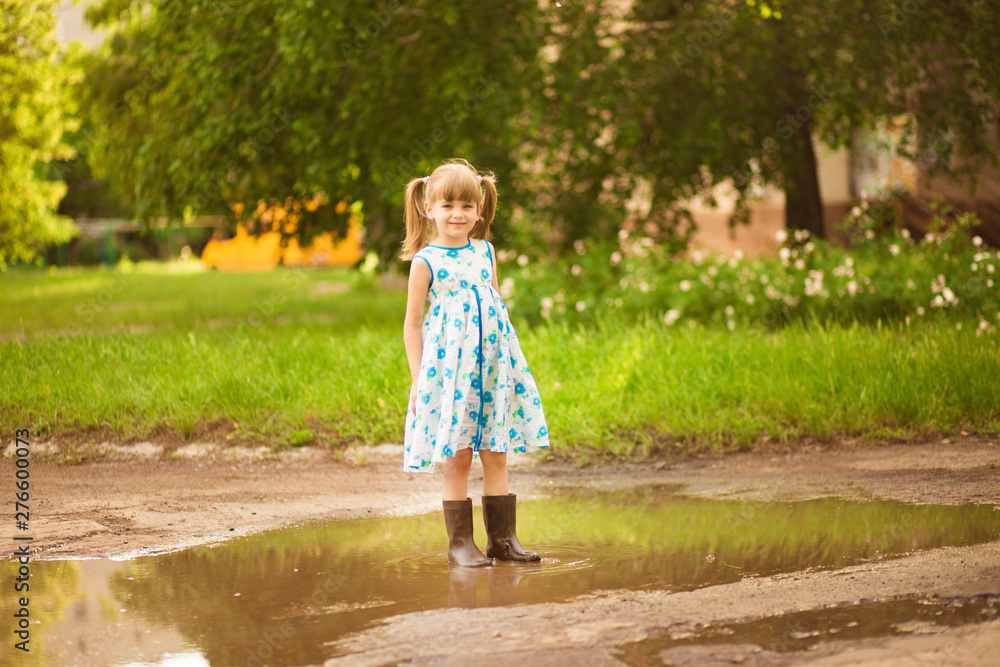 Naklejka premium Little kid girl runs through a puddle. summer outdoor