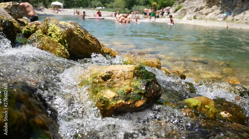 Castelcivita, Campania, Salerno, Italy - June 23 2019: bathers on the Calore river in the summer with a water source in the foreground. People swim and have fun in the river photo