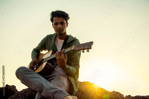 A young gentleman with a melodious  guitar photo