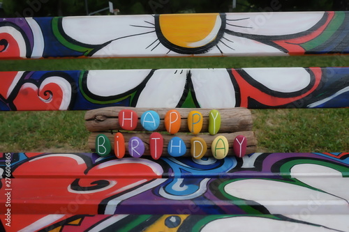 Happy Birthday text with colored stones on a creative painted public bench 