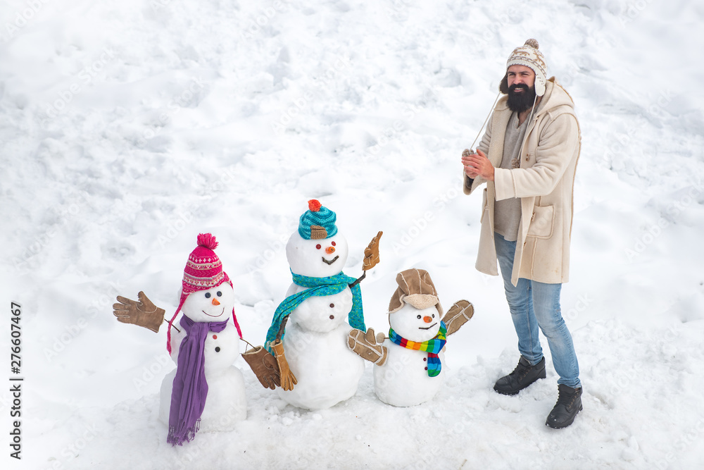 Winter scene with snowman on white snow background. Happy winter snowman family. Mother snow-woman, father snow-man and kid wishes merry Christmas and Happy New Year.