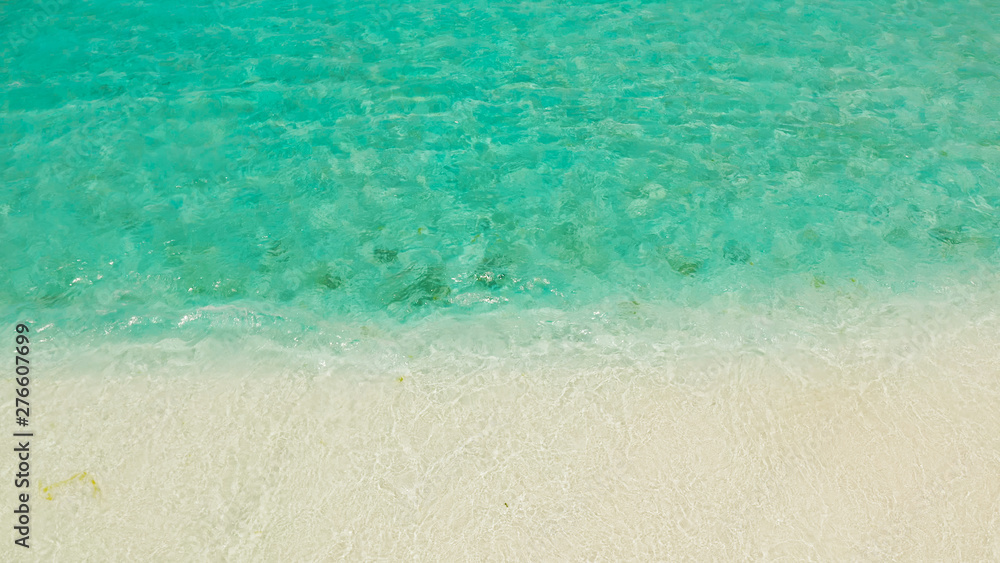 Obraz premium Sandy beach with and azure water of the lagoon,copy space for text, top view. Sea water surface in lagoon. Transparent turquoise ocean water surface. Background texture