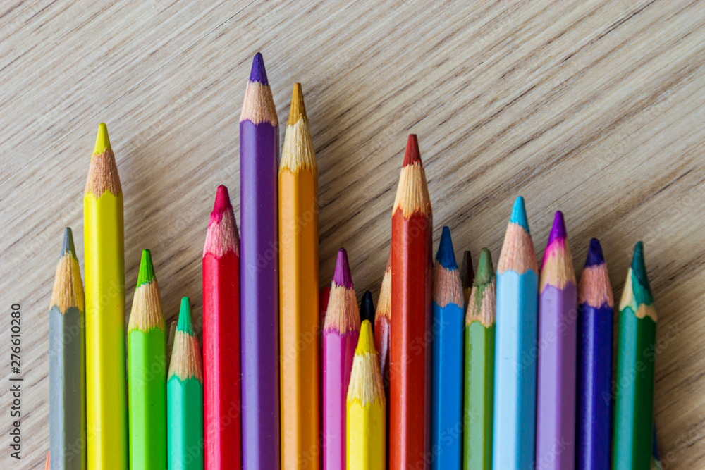 The group of a different length colored drawing pencils are laying on the wooden desk background and waiting for a painting lesson. The group of a different length colored drawing pencils are laying on the wooden desk background and waiting for a painting lesson.