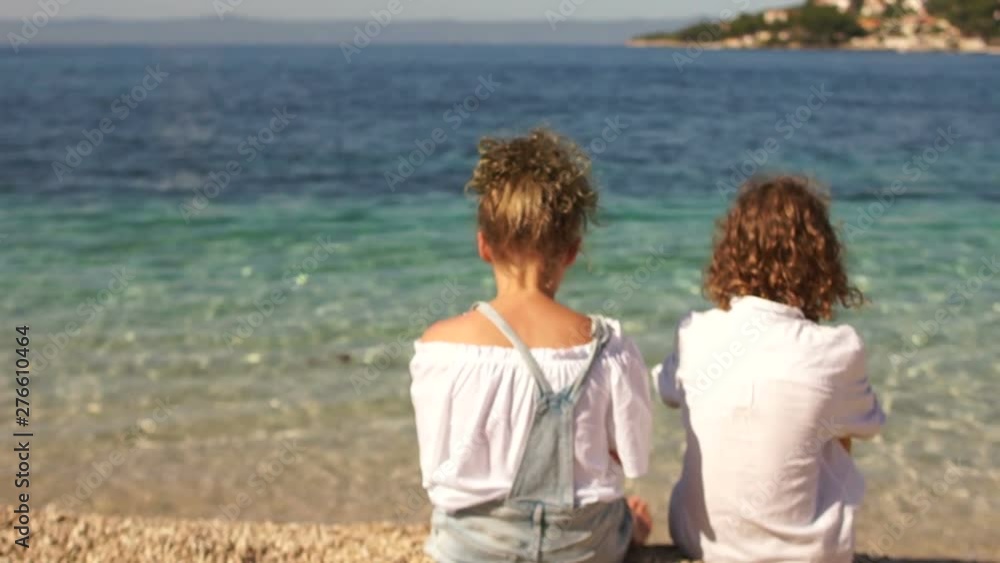 Rear view of happy lovers little boy and girl on the shore of the clear sea. First love, travel concept, brother and sister Rear view of happy lovers little boy and girl on the shore of the clear sea. First love, travel concept, brother and sister