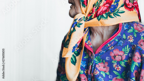very old wrinkled senior woman in a head scarf and colorful cloth. Aging process- neck, mouth, nose of elderly woman toothless. Side view. copy space. Coronavirus risk group. COVID virus infection.