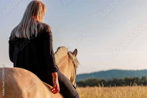 Fotografia Woman sitting on Norwegian Fjord Horse and the sun shines on the horse fur