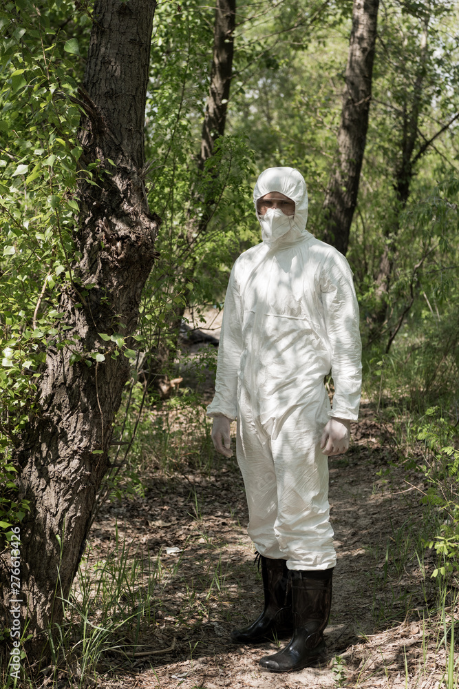 full length view of ecologist in protective costume and respirator in forest full length view of ecologist in protective costume and respirator in forest