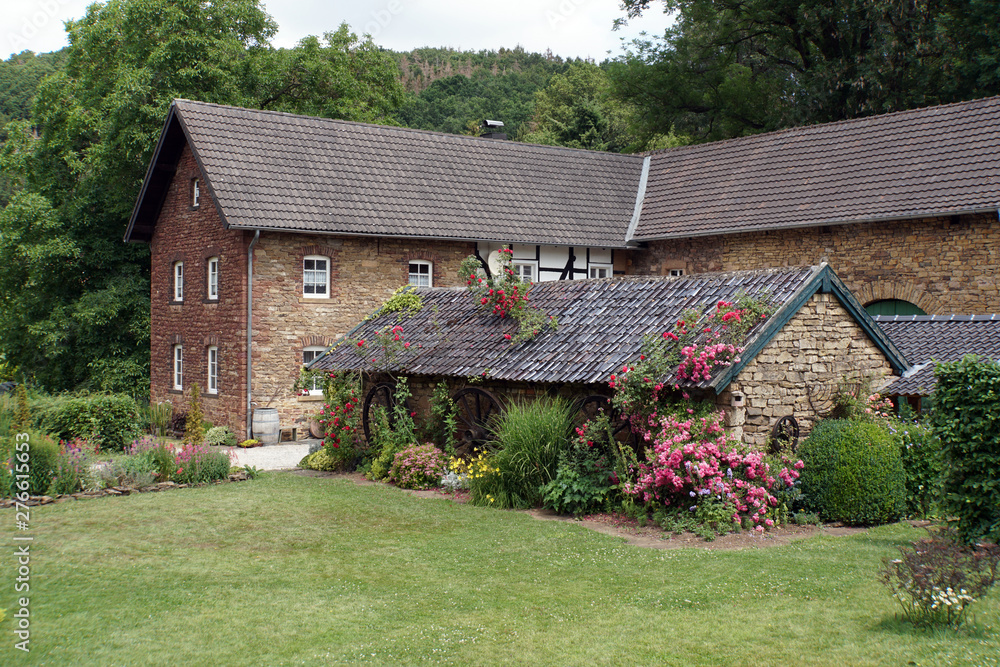 Fototapeta premium bunter Bauerngarten vor altem Bauernhaus