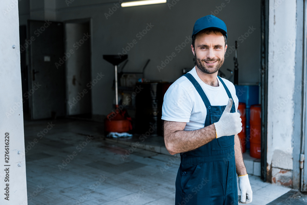 handsome bearded car mechanic in cap standing and showing thumb up handsome bearded car mechanic in cap standing and showing thumb up