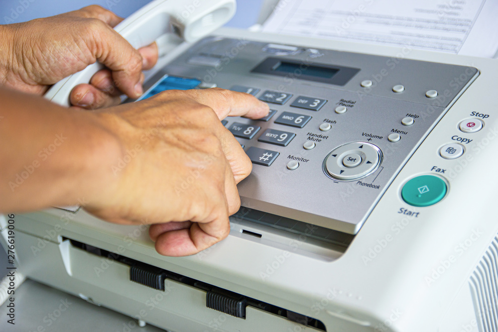 hand man are using a fax machine in the office hand man are using a fax machine in the office