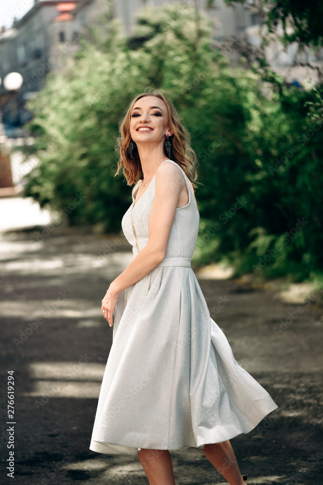 Gorgeous young model woman with perfect hair looking at camera posing in the city wearing evening dress. Gorgeous young model woman with perfect hair looking at camera posing in the city wearing evening dress.