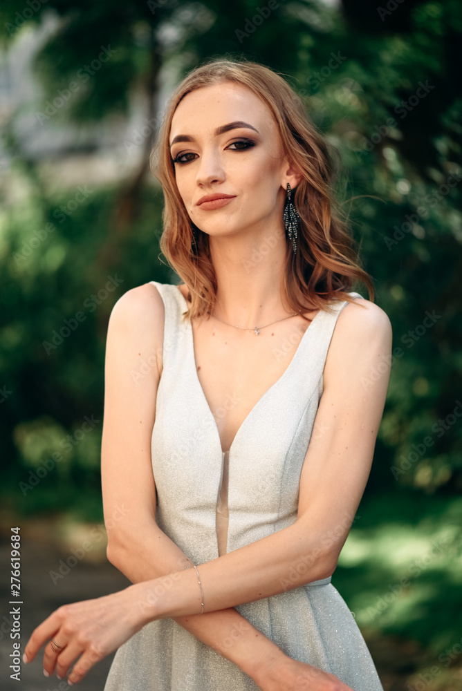 Gorgeous young model woman with perfect hair looking at camera posing in the city wearing evening dress. Gorgeous young model woman with perfect hair looking at camera posing in the city wearing evening dress.