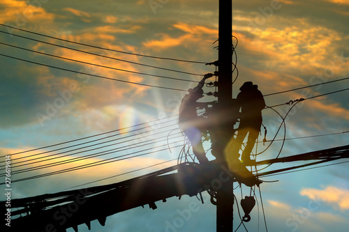 Silhouette people electrician working high on sky background.