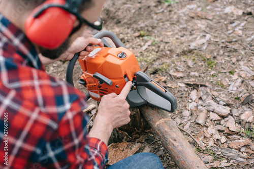 Wallpaper Mural selective focus of lumberjack in hearing protectors repairing chainsaw in forest Torontodigital.ca