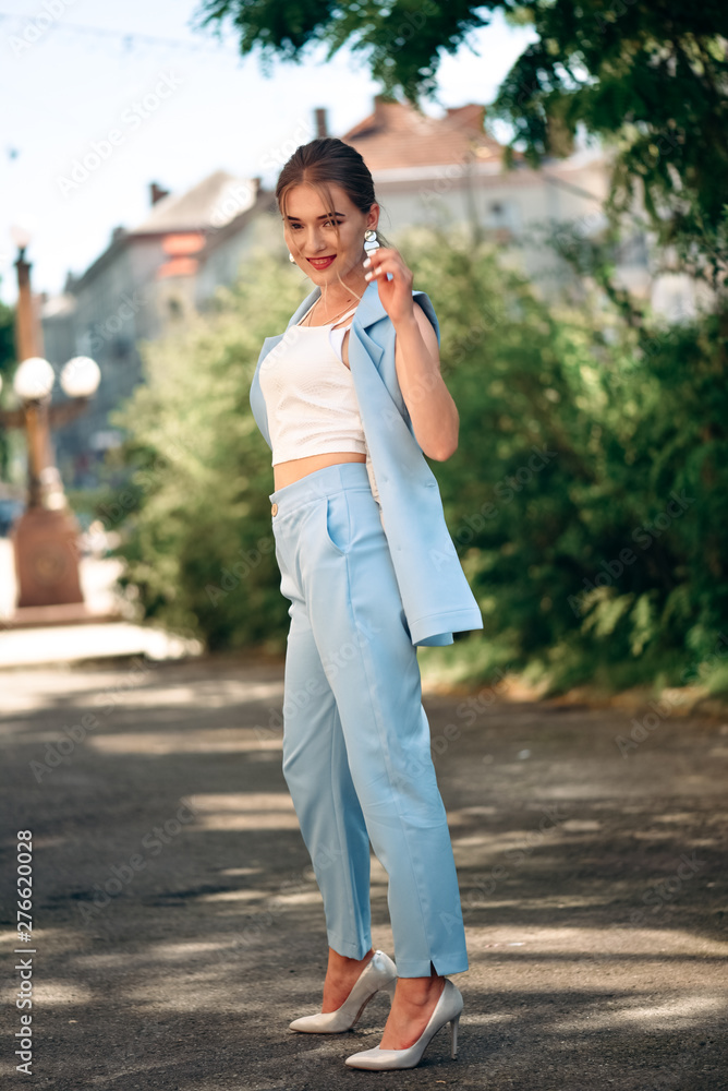Gorgeous young model woman with perfect hair looking at camera posing in the city wearing classic costume. Gorgeous young model woman with perfect hair looking at camera posing in the city wearing classic costume.