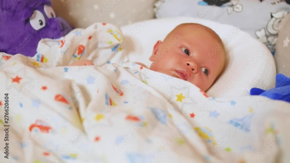 Close-up portrait of a nice newborn baby in a crib. Protection of children. Newborn health. Close up shot. Close-up portrait of a nice newborn baby in a crib. Protection of children. Newborn health. Close up shot.