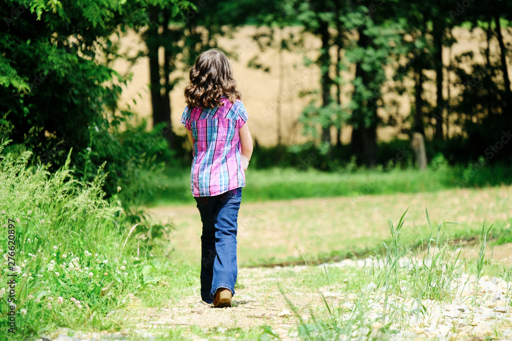Child walking on path in rural field outdoors during summer. Farm lifestyle for kid. Child walking on path in rural field outdoors during summer. Farm lifestyle for kid.