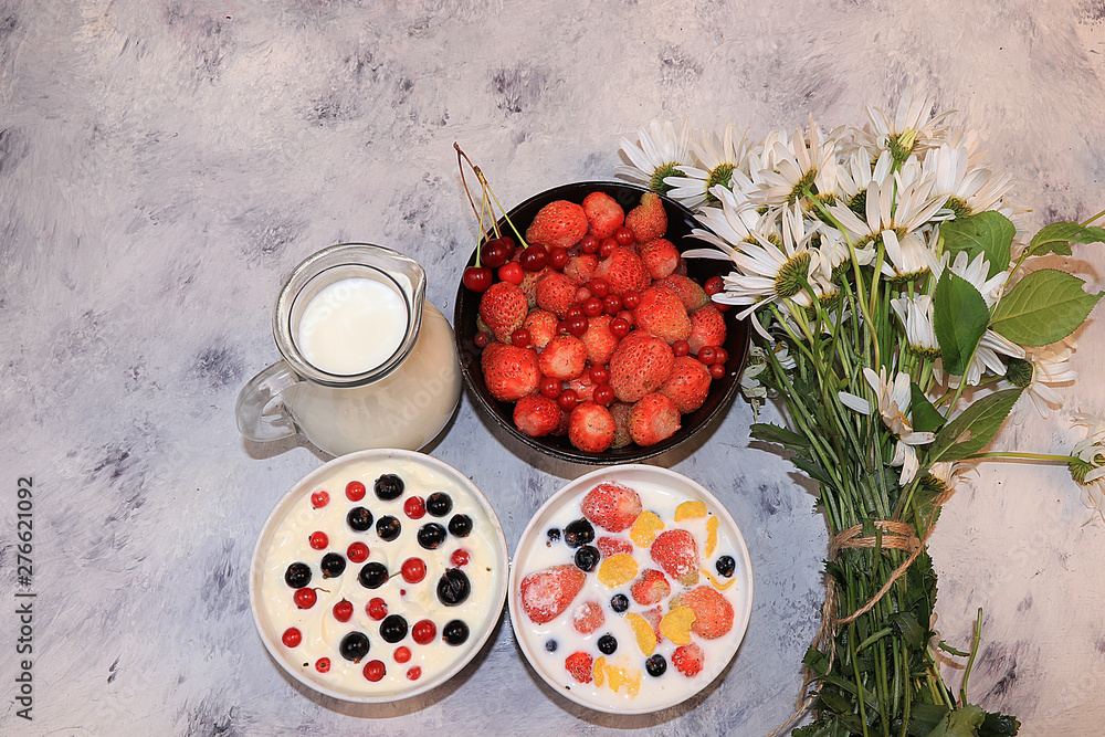 Strawberry yogurt, milk and ripe berries of currants and strawberries on a light background.