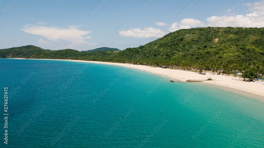 Aerial view of Nacpan Beach, tropical beach in El Nido with palm trees and chystal water