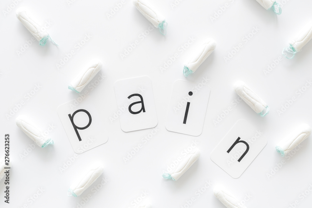 Gynaecologist and menstruation concept with tampons and pain word pattern on white background top view Gynaecologist and menstruation concept with tampons and pain word pattern on white background top view