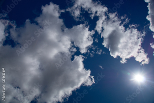 white fluffy clouds in the blue sky on a sunny summer day © Ilya Kaifat