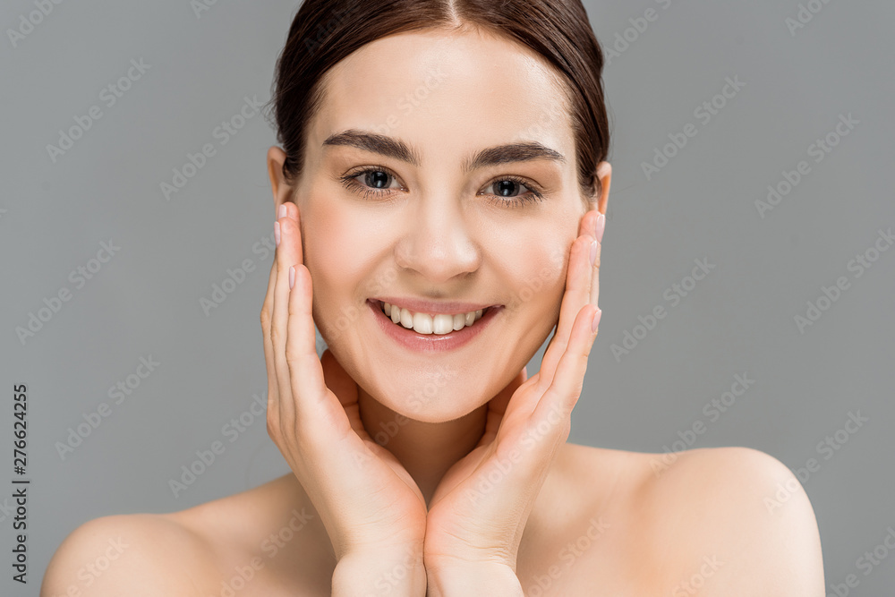 happy naked woman touching face and looking at camera isolated on grey happy naked woman touching face and looking at camera isolated on grey