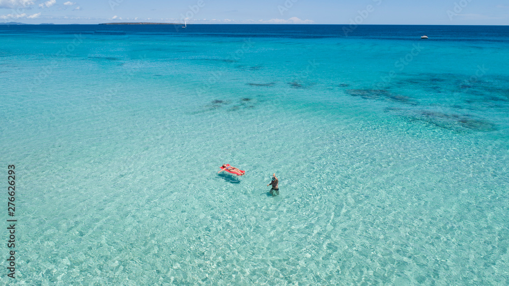 Couple on vacation at the beach, one of them with an inflatable mattress. Formentera crystal clear water Couple on vacation at the beach, one of them with an inflatable mattress. Formentera crystal clear water