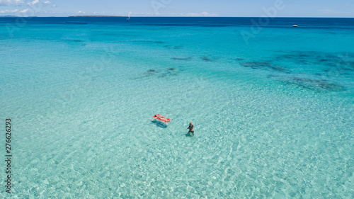 Couple on vacation at the beach, one of them with an inflatable mattress. Formentera crystal clear water