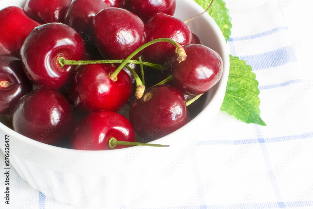 Fresh cherry in white ceramic bowl on wooden white background. Fresh cherry in white ceramic bowl on wooden white background.