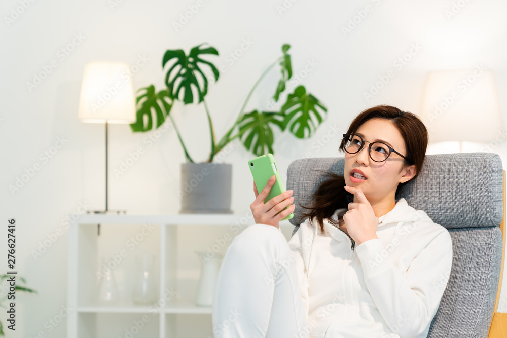 部屋でスマホを見る女性 考える 部屋でスマホを見る女性 考える