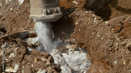 Wallpaper Mural SLOW MOTION, CLOSE UP: Pneumatic jackhammer creates a cloud of grey dust as it strikes against solid rock sitting in the soil at a busy construction site. Heavyweight drill crushing stones and dirt. Torontodigital.ca