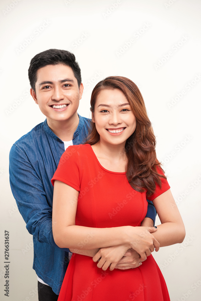Portrait of a young couple hugging and standing against white background Portrait of a young couple hugging and standing against white background