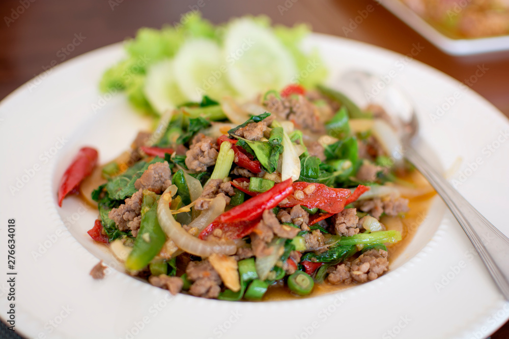 Spicy fried pork with basil leaves in white dish, Thai menu Spicy fried pork with basil leaves in white dish, Thai menu