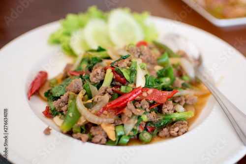 Spicy fried pork with basil leaves in white dish, Thai menu