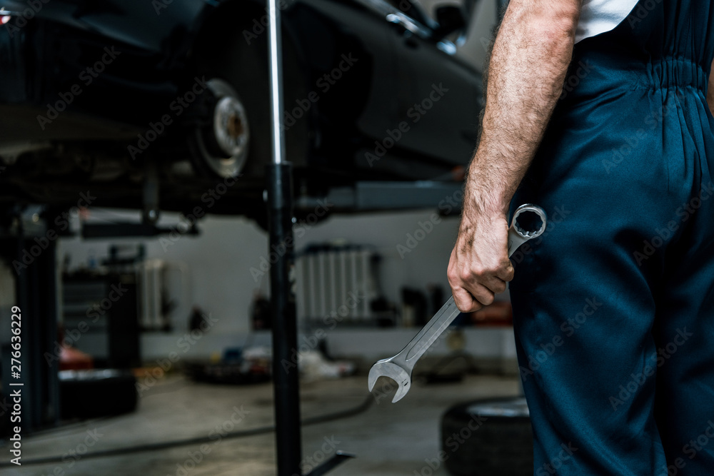 cropped view of car mechanic holding hand wrench in car repair station