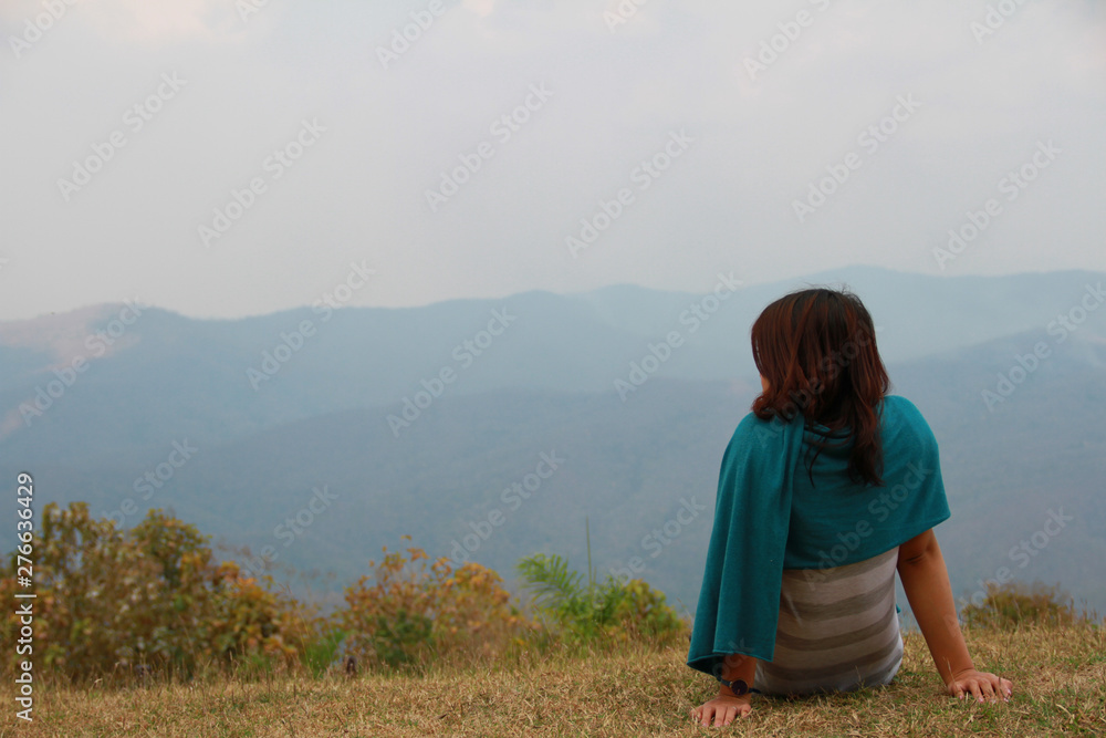 Lonely girl sit and look at the horizon of sky and the natural mountain. Miss lover on valentine's day