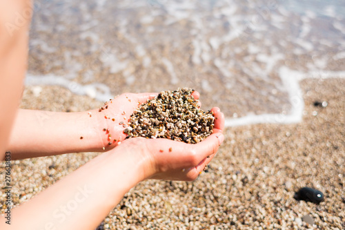 A girl sits on the beach and holds sand in her hands.