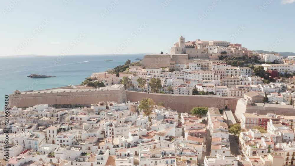 Aerial view of Ibiza city, the Old Town and the city walls of Eivissa, in the island of Ibiza, on a sunny and clear day, just after sunrise, with birds flying alongside the city wall. Aerial view of Ibiza city, the Old Town and the city walls of Eivissa, in the island of Ibiza, on a sunny and clear day, just after sunrise, with birds flying alongside the city wall.