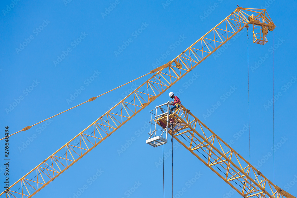 Workers on a large construction crane on blue sky