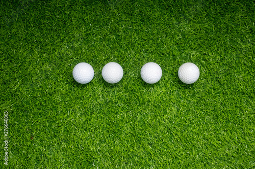 Four golf balls are on green grass