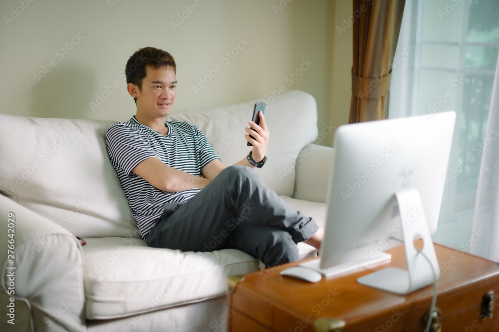 Young man sitting comfortably with laptop searching hotel accommodations online trying to save on hotel stays booking a room checking out a selection of resorts Young man sitting comfortably with laptop searching hotel accommodations online trying to save on hotel stays booking a room checking out a selection of resorts