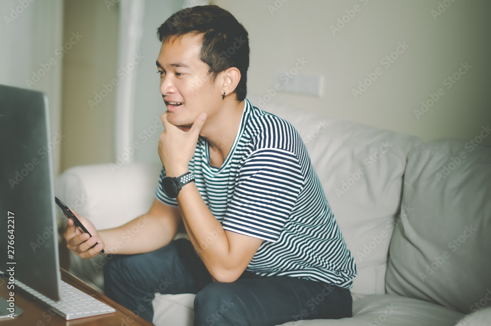 Young man sitting comfortably with laptop searching hotel accommodations online trying to save on hotel stays booking a room checking out a selection of resorts Young man sitting comfortably with laptop searching hotel accommodations online trying to save on hotel stays booking a room checking out a selection of resorts