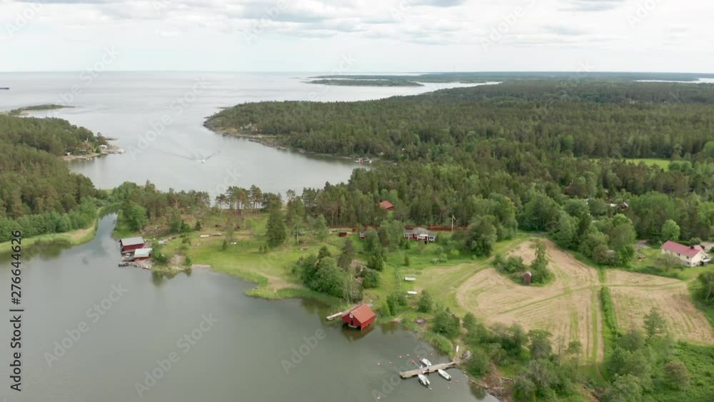 Sunny summer morning in Sweden. Aerial view over the Swedish archipelago. Drone flies forward over the sea, green forests and red huts. Fishing cabins and bouthouses along the shoreline. Sunny summer morning in Sweden. Aerial view over the Swedish archipelago. Drone flies forward over the sea, green forests and red huts. Fishing cabins and bouthouses along the shoreline.