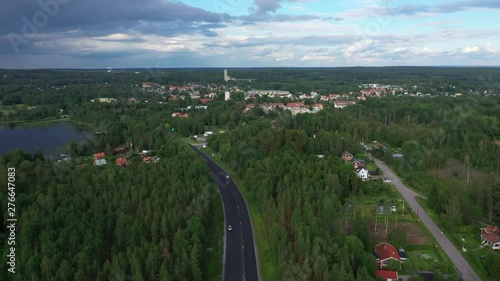 Pedestal ascending drone footage over a highway running through the forest and a small town with a church and a mining tower. A small lake is visible on the left hand side Filmed in realtime at 4k. photo