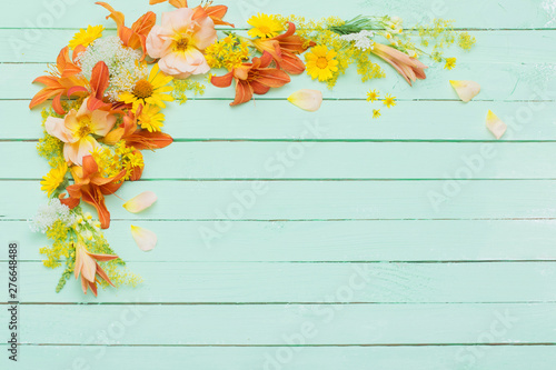 yellow and orange flowers on green wooden background