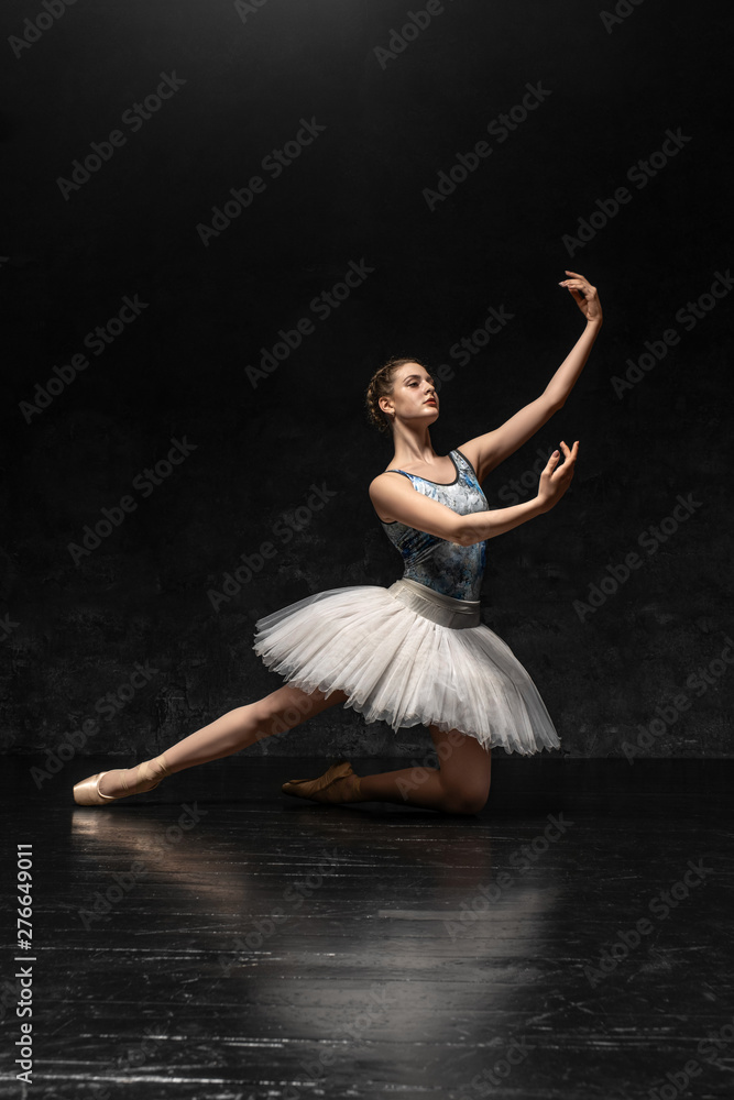 Ballerina. A young graceful ballerina dressed in professional attire, pointe shoes with ribbons and a white tutu, demonstrates dance skills. Beautiful classic ballet.