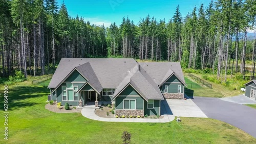 4k footage of an American suburban home surrounded by evergreen trees, aerial view with drop down approach to ground level