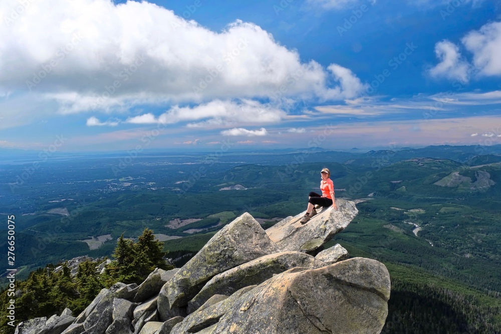 Woman hiker on rock above valley. Mount Pilchuck State Park near Seattle. Washington. United States of America
