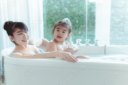Young asian mother and daughter in a bathroom happy smiling taking bath
