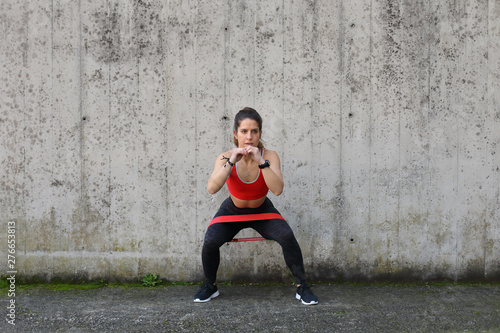 Urban fitness outdoor workout with resistance band. Young fit woman doing banded Step-Outs.